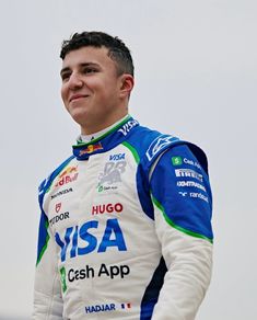 a man in a blue and white racing suit with his hands on his hips smiling