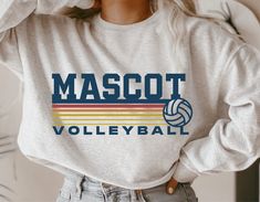 a woman wearing a sweatshirt with the word mascott volleyball on it and a volleyball ball