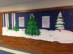 a bulletin board decorated with christmas trees and snow on the ground in front of a brick wall