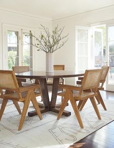 a dining table with chairs around it and a vase on the table next to it