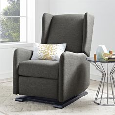 a gray recliner chair with a pillow on top of it and a side table next to it