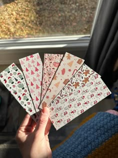 someone holding up some paper in front of a window with trees and snowflakes on it