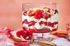 a trifle with strawberries and whipped cream in a glass dish on a table