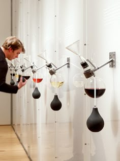 a man standing in front of a wall with wine glasses hanging from it's hooks