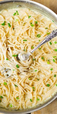 a bowl filled with pasta and peas on top of a wooden table