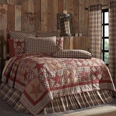 a bed in a room with wooden walls and plaid bedspread on top of it