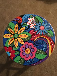 a colorful painted plate sitting on the floor