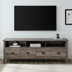 an entertainment center with drawers and a flat screen tv mounted on the wall above it