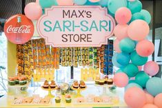 an assortment of desserts and drinks on display at a store with balloons in the background