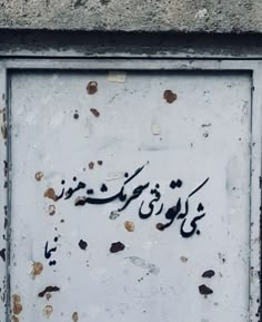 an arabic writing on the side of a building in front of a wall with peeling paint