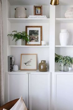 a white shelf filled with vases and plants on top of it's shelves