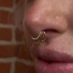 a close up of a woman's nose with an earring in the shape of a crescent