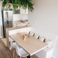 a kitchen table with white chairs and a plant hanging from the ceiling in front of it