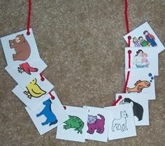 children's handmade cards with pictures of animals hanging from red string on carpet