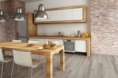 a dining room table surrounded by chairs and an open kitchen area with exposed brick walls