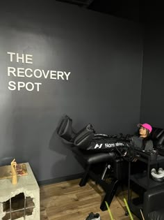 a woman sitting in a reclining chair next to a wall with the recovery spot written on it