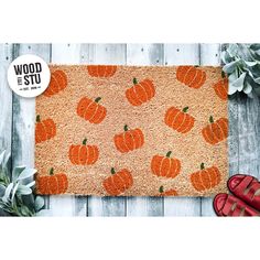 a door mat with pumpkins on it next to red shoes and succulent plants