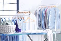 an ironing board with clothes on it next to a laundry basket and drying rack