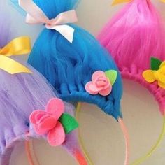 three colorful wigs with bows and flowers on them, one has a bow at the top