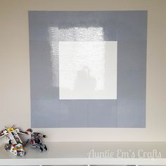 a white shelf with legos on top of it in front of a gray and white wall