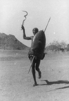 an old photo of a man holding a spear