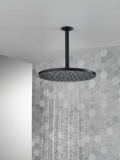 a shower head with water running down it's side and hexagonal tiles on the wall behind it