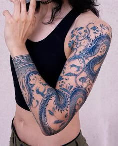 a woman with tattoos on her arm holding a cell phone