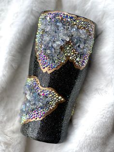 a black and gold glittered vase sitting on top of a white blanket