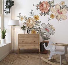 a room with flowers painted on the wall and a rocking chair in front of it