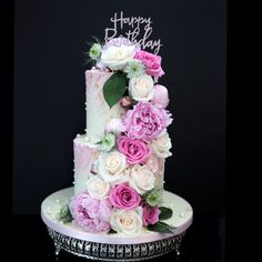 a birthday cake decorated with pink and white flowers