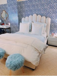 a bedroom with blue and white wallpaper, bedding and pillows on the floor