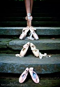 two pairs of ballet shoes sitting on top of some steps with their feet in the air