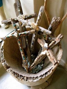 a bowl made out of driftwood with beads and stones in the center, sitting on a table next to a window