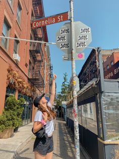 a woman is pointing at a street sign