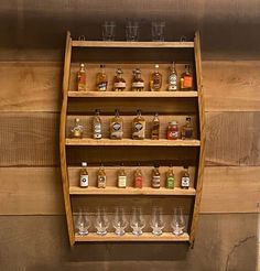 a wooden shelf filled with lots of bottles and glasses on top of a wall covered in wood planks