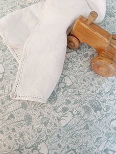 a wooden toy car sitting on top of a white cloth covered tablecloth next to an empty napkin