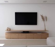 a flat screen tv mounted to the side of a wall in a white living room