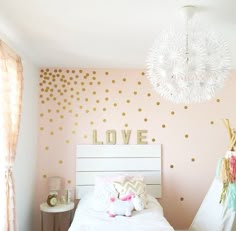 a bedroom decorated in pink and gold with polka dots on the walls, bedding and pillows