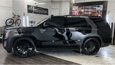 a black and white suv parked inside of a garage next to a bike on the wall