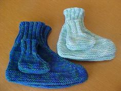 two knitted shoes sitting next to each other on a wooden table, one blue and the other green