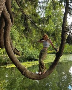 a woman is standing on a tree branch in the water