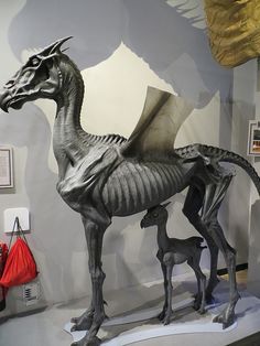 a statue of a dragon and its baby on display in a museum setting with other items