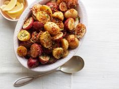 a white bowl filled with potatoes next to lemon wedges