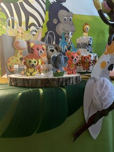 there are many different animals on display at this party table, including an animal themed cake topper and cupcakes