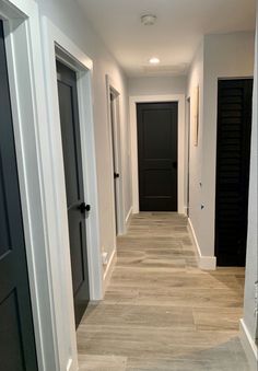 an empty hallway with black doors and white trim on the walls is seen in this image