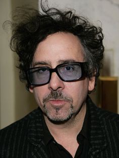 a man with black hair and glasses has a quote from tim burton on his face