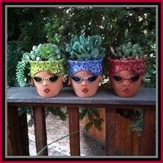 three pots with plants in them sitting on top of a wooden rail next to a fence