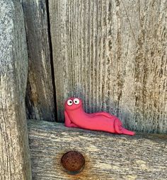 a pink slug sitting on top of a wooden fence