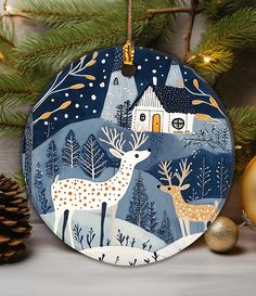 a christmas ornament with a deer and house in the background, surrounded by pine cones