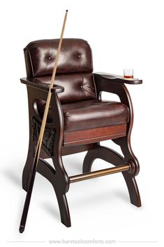 a brown leather chair with a wooden stick in it's arm and a glass on the table